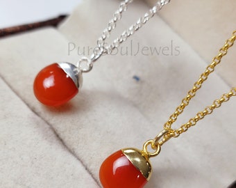 May include: Two necklaces with carnelian stone pendants. One necklace has a silver chain and the other has a gold chain. The carnelian stones are a vibrant orange color.