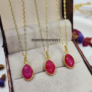 May include: Three gold chains with pink gemstone pendants. Each pendant is an oval shape with an eye design carved into the gemstone. The chains are displayed in a brown velvet box with the text "PURESOULJEWELS" printed on the box.