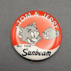 Op de afbeelding: Een rode en witte knop met de cartoonfiguren Tom en Jerry. De knop zegt "Tom & Jerry Go For Sunbeam".
