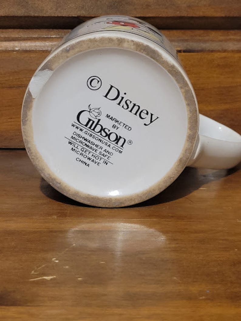 Puede incluir: Taza de cer&aacute;mica blanca con un dise&ntilde;o de personaje de Disney. La taza tiene un borde marr&oacute;n y un asa marr&oacute;n. La parte inferior de la taza tiene el texto "&copy; Disney" y "MARKETED BY Gibson&reg;", junto con la direcci&oacute;n del sitio web "www.gibsonusa.com". La taza es apta para lavavajillas y microondas, pero se calentar&aacute; en el microondas. Est&aacute; hecha en China.