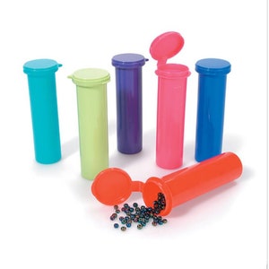 Könnte beinhalten: Sechs bunte Plastik-Pillendosen mit Deckeln, eine davon offen mit herausfallenden schwarzen Perlen. Die Dosen sind türkis, grün, lila, rosa und blau.