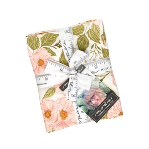 Può includere: Una pila di tessuto piegato con un motivo floreale di fiori rosa chiaro e foglie verde oliva su sfondo crema. Il tessuto è legato con un nastro bianco stampato con un design a righello e un'etichetta con la scritta Moda Fabrics Supplies.