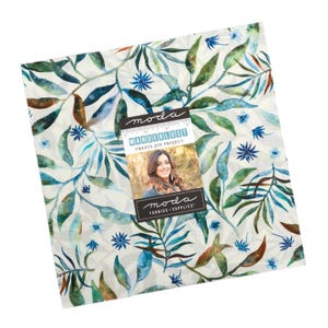 May include: A white fabric with a watercolour pattern of blue and green leaves and flowers. The fabric has the text "moda" and "Wanderlust Create Joy Project" on a label.