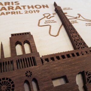 May include: A wooden cutout of the Eiffel Tower and Notre Dame Cathedral, with the text "PARIS MARATHON 14 APRIL 2019" above the cutouts.