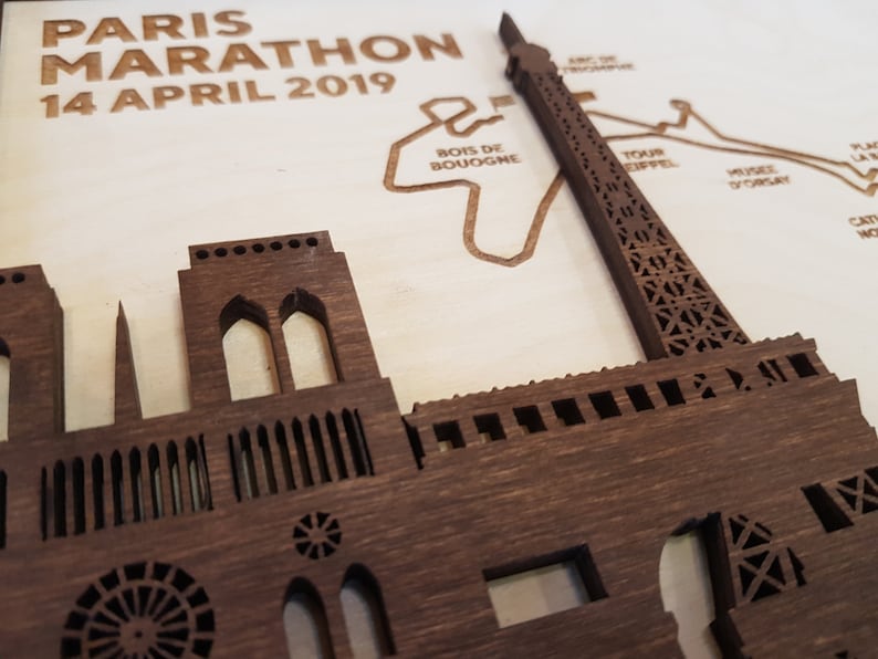 May include: A wooden cutout of the Eiffel Tower and Notre Dame Cathedral, with the text "PARIS MARATHON 14 APRIL 2019" above the cutouts.