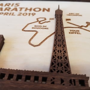 May include: A wooden plaque with a laser-cut design of the Paris Marathon route, featuring the Eiffel Tower, Arc de Triomphe, and other landmarks. The text "PARIS MARATHON 14 APRIL 2019" is at the top of the plaque.