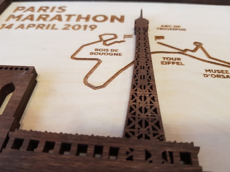 May include: A wooden plaque with a laser-cut design of the Paris Marathon route, featuring the Eiffel Tower, Arc de Triomphe, and other landmarks. The text "PARIS MARATHON 14 APRIL 2019" is at the top of the plaque.