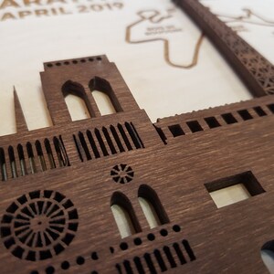 May include: A close-up of a wooden model of the Notre Dame Cathedral in Paris, France. The model is intricately detailed, with visible windows, arches, and a circular rose window.