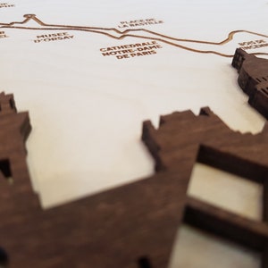 May include: A wooden map of Paris with the names of famous landmarks, including the Eiffel Tower, the Louvre, and Notre Dame Cathedral.