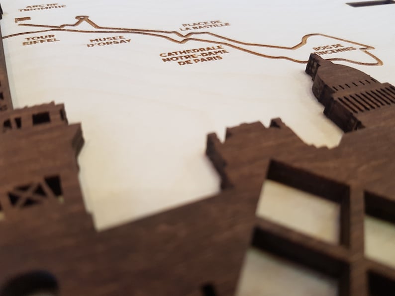 May include: A wooden map of Paris with the names of famous landmarks, including the Eiffel Tower, the Louvre, and Notre Dame Cathedral.