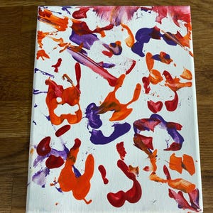 Op de afbeelding: Abstract canvas kunstwerk met een witte achtergrond en levendige spatten van rode, oranje en paarse verf. Het kunstwerk toont een verscheidenheid aan penseelstreken en spetters, met het nummer "#3" in goud aan de onderkant.