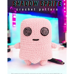 May include: A light pink crocheted plush toy with two black spiral eyes and a small black horizontal line for a mouth. The text SHADOW SPRITE crochet pattern appears at the top, and a disclaimer about personal use is at the bottom.