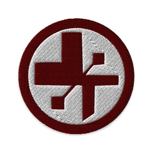 Peut inclure: Un écusson brodé rouge et blanc avec un motif de croix. La croix est entourée d'un cercle rouge.