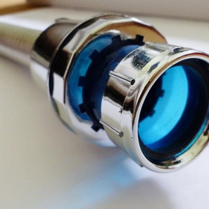 Könnte beinhalten: Eine verchromte Metall-Armaturenerweiterung mit einem blauen Kunststoffeinsatz. Die Erweiterung hat ein Gewindeende zum Anschließen an eine Armatur.