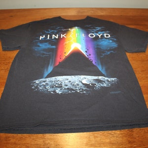 May include: Black t-shirt featuring a graphic of a rainbow and a mountain on the moon. The text "PINK FLOYD" is printed above the graphic.
