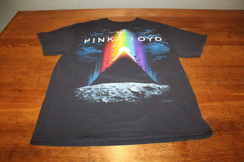 May include: Black t-shirt featuring a graphic of a rainbow and a mountain on the moon. The text "PINK FLOYD" is printed above the graphic.