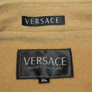 May include: Black label with white text reading "VERSACE JACKET COUTURE" and "XL" on a brown fabric background.