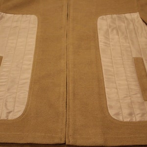 May include: A brown jacket with a zipper closure and two white quilted panels on the front.