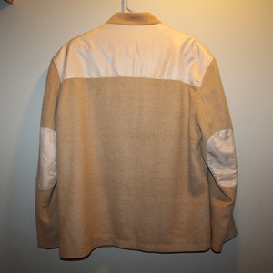 May include: A beige blazer with white elbow patches. The blazer has a white collar and a single button closure.