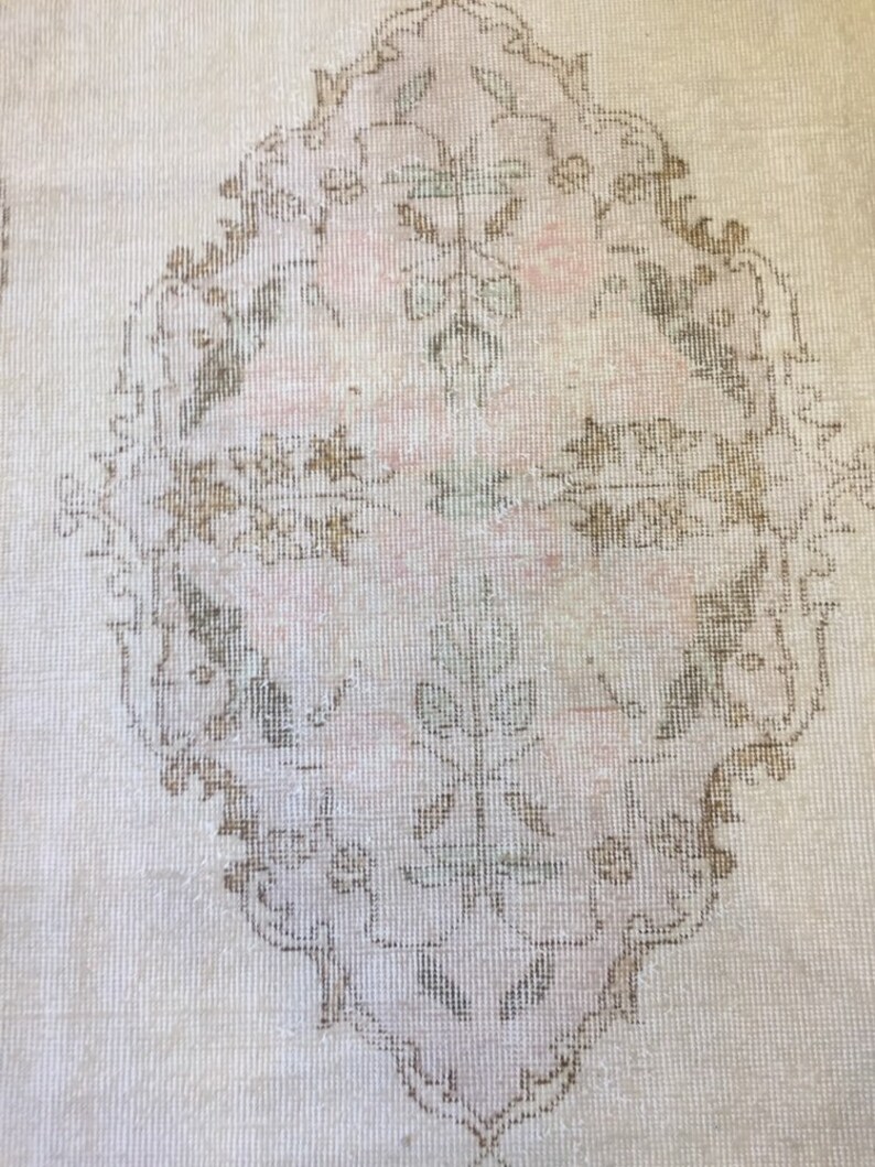 May include: A vintage rug with a delicate floral pattern in shades of brown and beige. The rug has a distressed look, with faded colors and a worn texture.