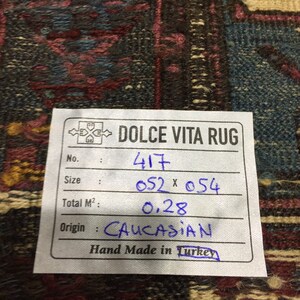 May include: A white tag with black text and blue handwritten text. The tag reads "DOLCE VITA RUG" and includes information about the rug, such as the number, size, total square metres, origin, and that it is hand-made in Turkey. The tag is on a dark brown and blue patterned rug.