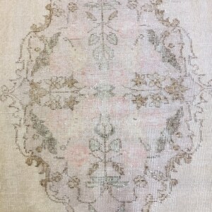 May include: A vintage rug with a light beige background and a large, intricate floral design in shades of brown and pink.