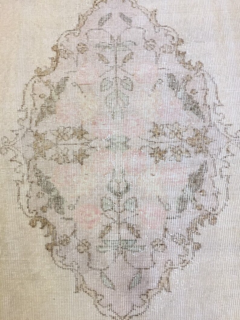 May include: A vintage rug with a light beige background and a large, intricate floral design in shades of brown and pink.