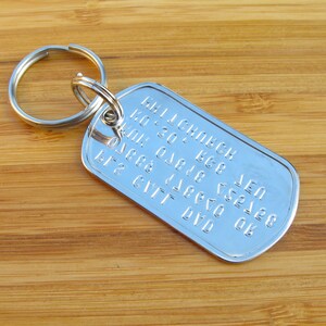 May include: Silver keychain with a dog tag featuring the text "MILLENBECK  LEN  K0 30  K68  01 0 018  7528  08  6777  DYO".