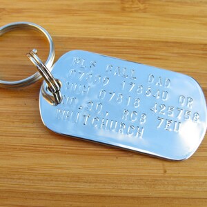 May include: Silver dog tag keychain with the text "PLS CALL DAD 07889 178640 OR MUM 07818 425758 NO. 30, RC8 7EU WHITCHURCH"