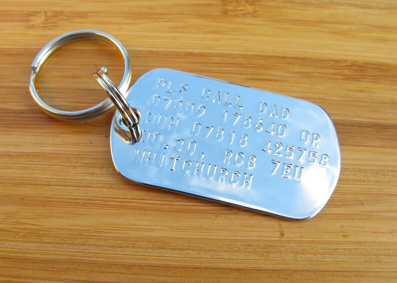 May include: Silver dog tag keychain with the text "PLS CALL DAD 07889 178640 OR MUM 07818 425758 NO. 30, RC8 7EU WHITCHURCH"