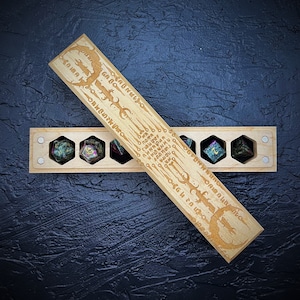May include: Wooden box with a lid that has a dragon design and runes engraved on it. The box is open and contains six dice with green, black, and white swirls.