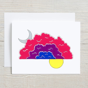 May include: A greeting card with a whimsical illustration of a crescent moon, a sun, and layered clouds in shades of pink, purple, and blue.