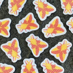 May include: A collection of 15 embroidered iron-on patches featuring a moth design in shades of pink and yellow. The patches are on a white background.