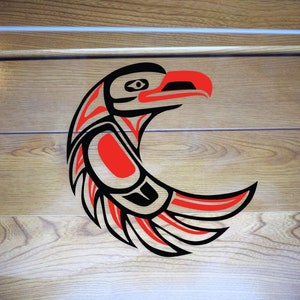 Peut inclure: Panneau rectangulaire transparent avec un motif d'aigle amérindien stylisé. L'œuvre utilise des couleurs noir, rouge et blanc. Le fond est une surface en bois.