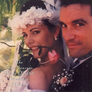 May include: A bride and groom pose for a wedding photo. The bride is wearing a white dress and a floral headpiece. The groom is wearing a black suit and a white shirt. The text "The Four Seasons String Quartet Wedding Album" is visible in the image.