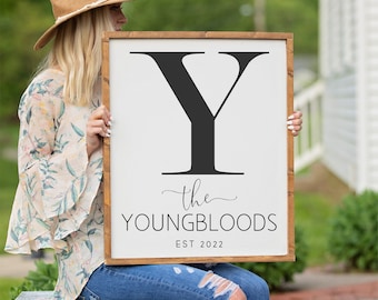 May include: A white wooden sign with a black letter Y, the text "the YOUNG BLOODS EST 2022" and a brown wooden frame.