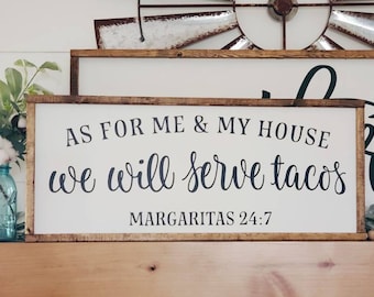 May include: A rustic wooden sign with white background and black lettering. The sign reads "As for me & my house we will serve tacos Margaritas 24:7".