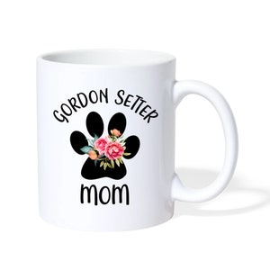 Puede incluir: Taza de caf&eacute; de cer&aacute;mica blanca con una huella de pata negra con flores rosas en su interior. El texto "Gordon Setter Mom" est&aacute; impreso en la taza.