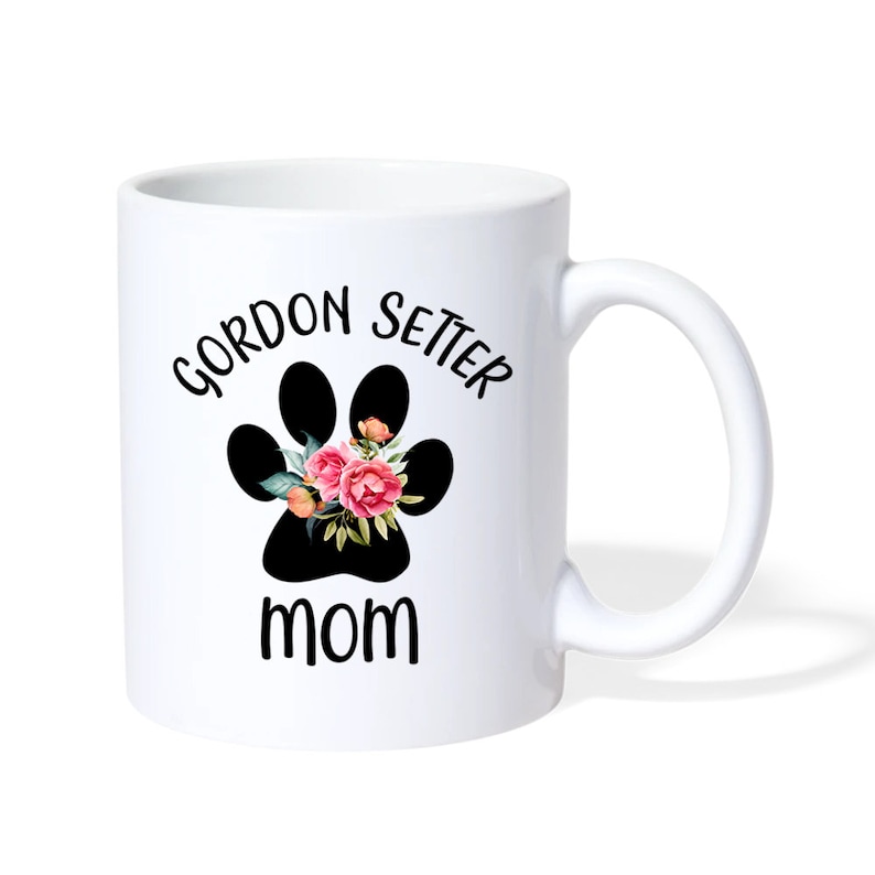 Puede incluir: Taza de caf&eacute; de cer&aacute;mica blanca con una huella de pata negra con flores rosas en su interior. El texto "Gordon Setter Mom" est&aacute; impreso en la taza.