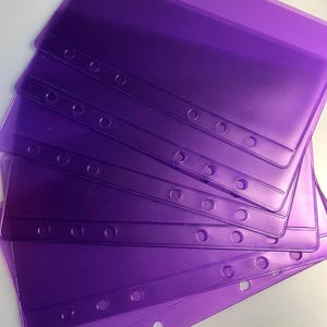 May include: A stack of translucent purple binder sheet protectors. Each protector has a reinforced edge with three holes for insertion into a binder. The protectors are made of a flexible plastic material.