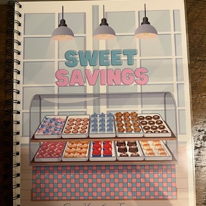 Peut inclure: Une couverture de carnet illustrée en rose et bleu avec le texte "Sweet Savings" et une vitrine remplie de pâtisseries colorées. La vitrine a un sol en carreaux à damier et le texte "Our Hometown Treasures" en bas.