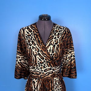 Puede incluir: Un vestido de envoltura de estampado de leopardo marr&oacute;n, negro y blanco con cuello en V y mangas 3/4.
