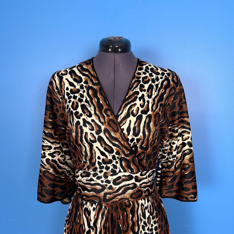 Puede incluir: Un vestido de envoltura de estampado de leopardo marr&oacute;n, negro y blanco con cuello en V y mangas 3/4.