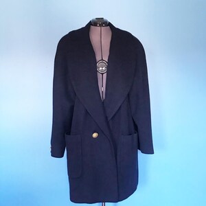 Pu&ograve; includere: Un cappotto di lana blu navy con un ampio colletto, due tasche e una chiusura con bottone dorato.