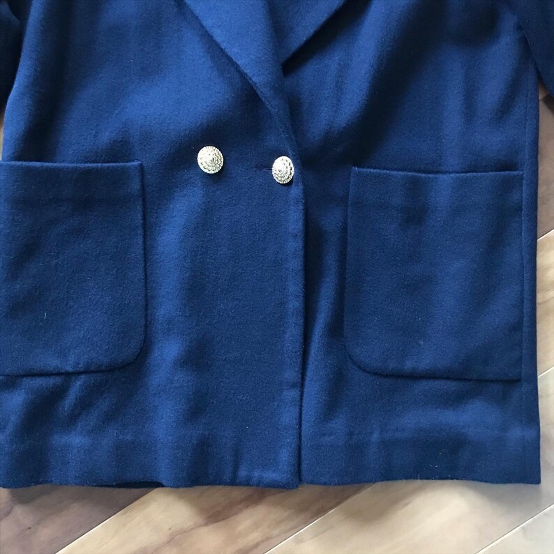 Pu&ograve; includere: Un blazer blu scuro doppiopetto con due tasche a patta e bottoni dorati.