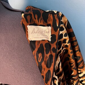 Puede incluir: Primer plano de una tela de estampado de leopardo marr&oacute;n y negro con una etiqueta blanca que dice "Dela-Z-Ann Creation Hand Washable".
