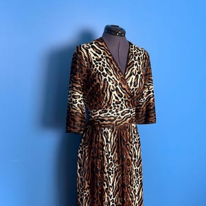 Puede incluir: Un vestido de envoltura de estampado de leopardo marr&oacute;n y blanco con cuello en V y mangas 3/4.