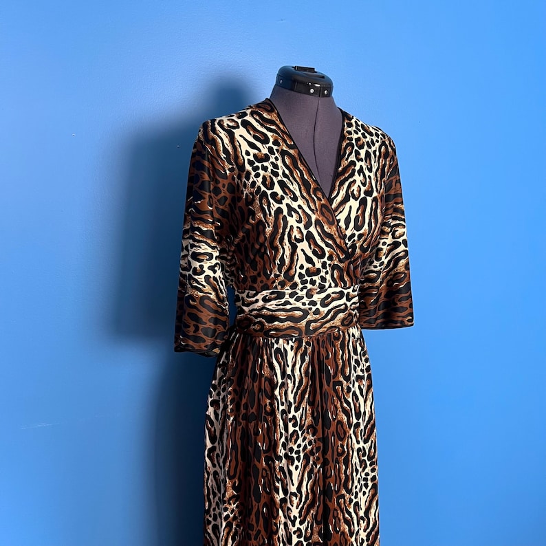 Puede incluir: Un vestido de envoltura de estampado de leopardo marr&oacute;n y blanco con cuello en V y mangas 3/4.