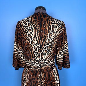 Puede incluir: Un vestido de estampado de leopardo marr&oacute;n y blanco con manga larga y cremallera en la espalda.