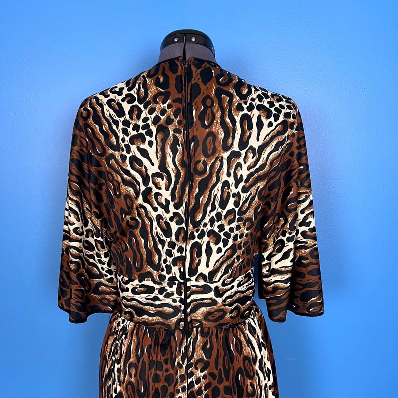 Puede incluir: Un vestido de estampado de leopardo marr&oacute;n y blanco con manga larga y cremallera en la espalda.